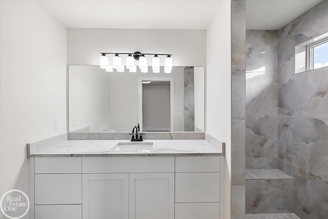 bathroom featuring tiled shower and vanity