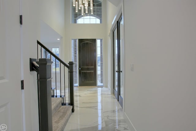 foyer entrance with baseboards, stairway, an inviting chandelier, a towering ceiling, and marble finish floor