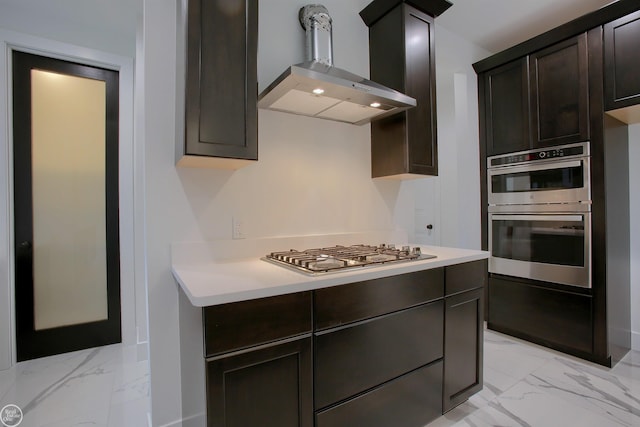 kitchen with stainless steel appliances, marble finish floor, wall chimney exhaust hood, and light countertops