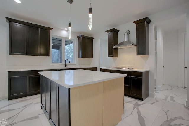 kitchen with a kitchen island, decorative light fixtures, sink, stainless steel gas cooktop, and wall chimney exhaust hood