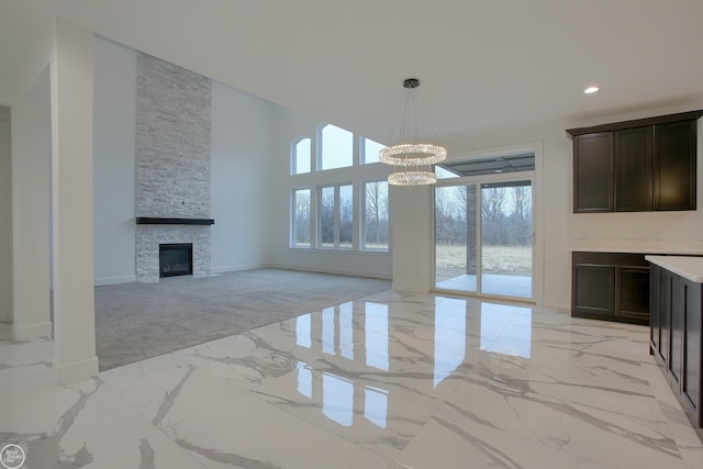 interior space with a fireplace, a chandelier, and a high ceiling