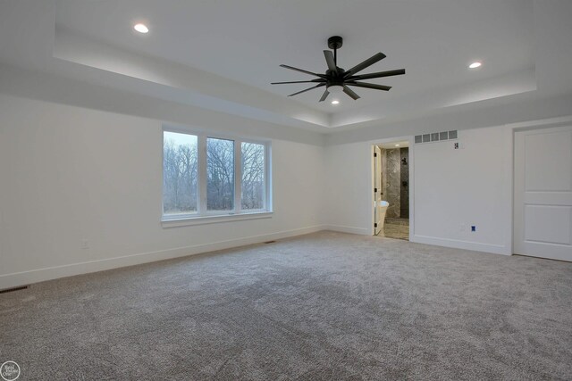 carpeted spare room featuring a tray ceiling and ceiling fan