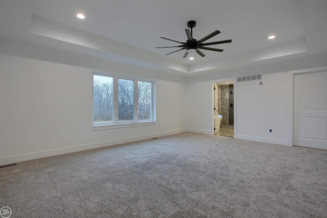 spare room with a tray ceiling, recessed lighting, and baseboards