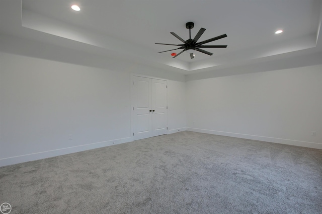 spare room with carpet floors, ceiling fan, and a tray ceiling