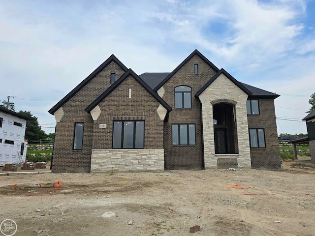 french country inspired facade featuring brick siding and stone siding