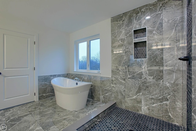 full bath featuring wainscoting, tiled shower, a freestanding tub, marble finish floor, and tile walls