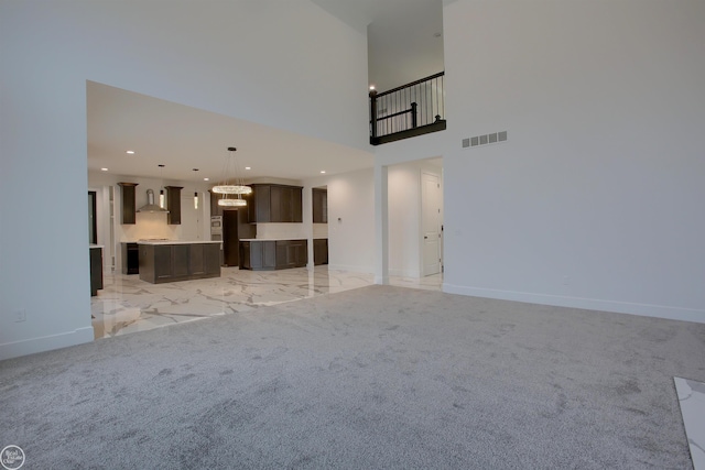 unfurnished living room featuring light colored carpet and a towering ceiling