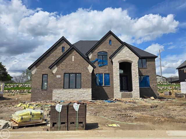 view of front of house featuring stone siding, brick siding, and roof with shingles