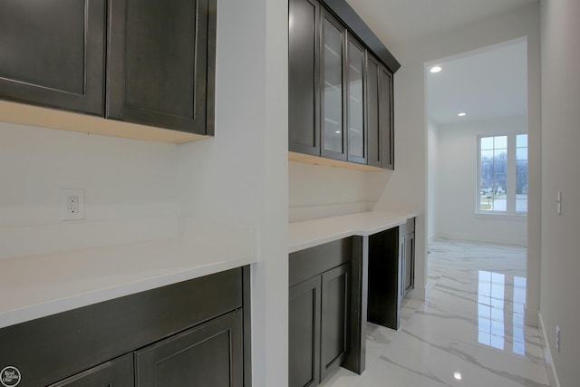 interior space featuring glass insert cabinets, baseboards, light countertops, recessed lighting, and marble finish floor