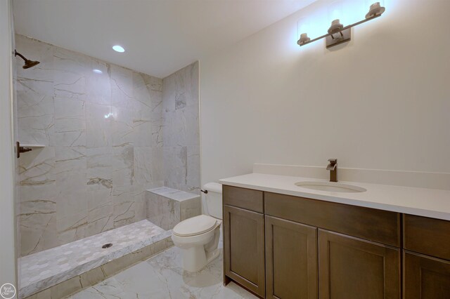 bathroom featuring vanity, toilet, and a tile shower