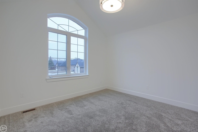 empty room with visible vents, baseboards, carpet, and vaulted ceiling