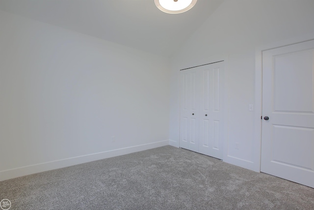 unfurnished bedroom featuring vaulted ceiling, carpet, baseboards, and a closet