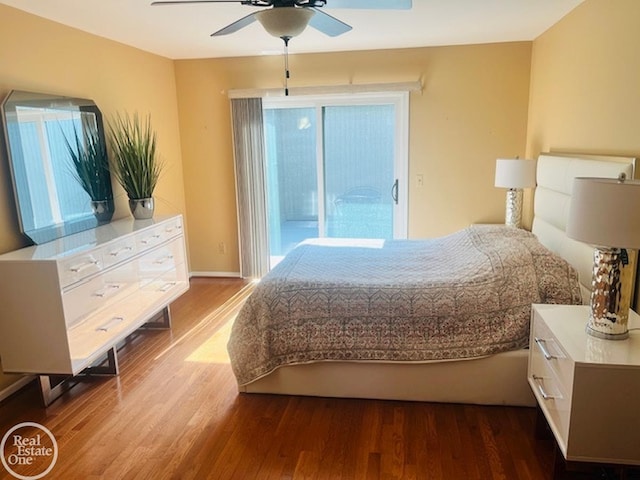 bedroom featuring baseboards, wood finished floors, a ceiling fan, and access to exterior