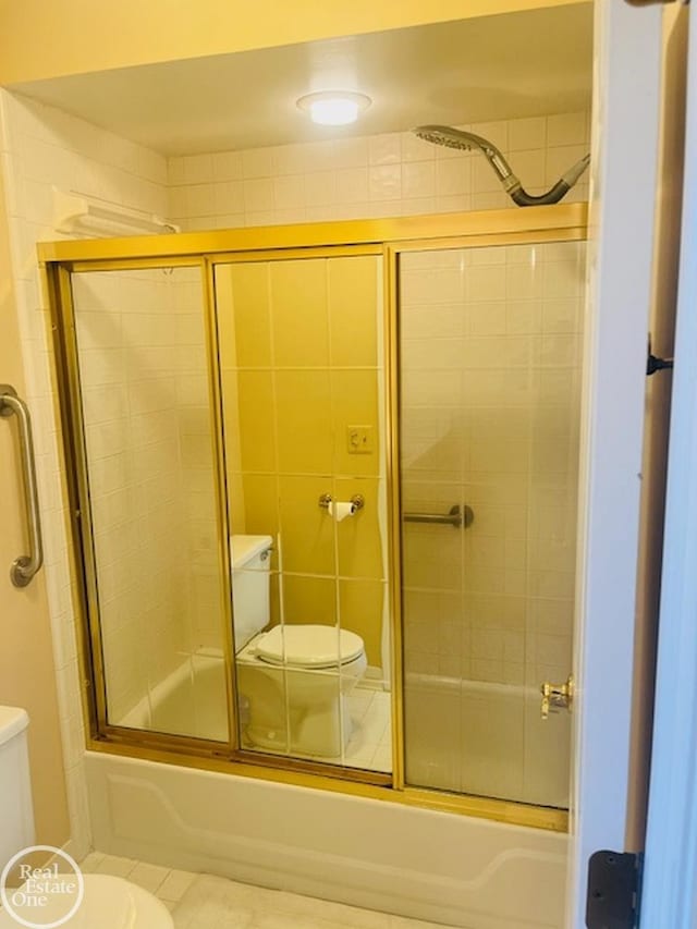 bathroom featuring toilet and combined bath / shower with glass door