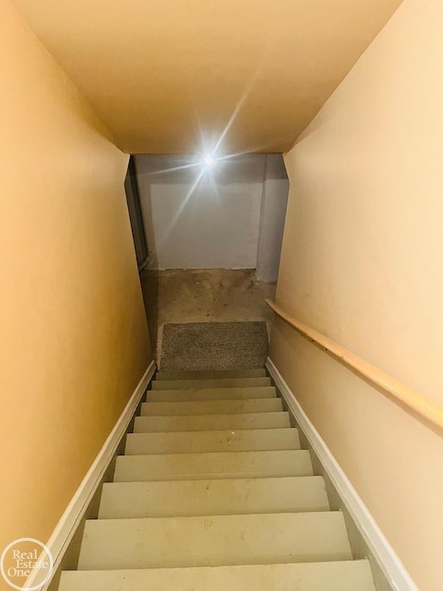 staircase with unfinished concrete flooring