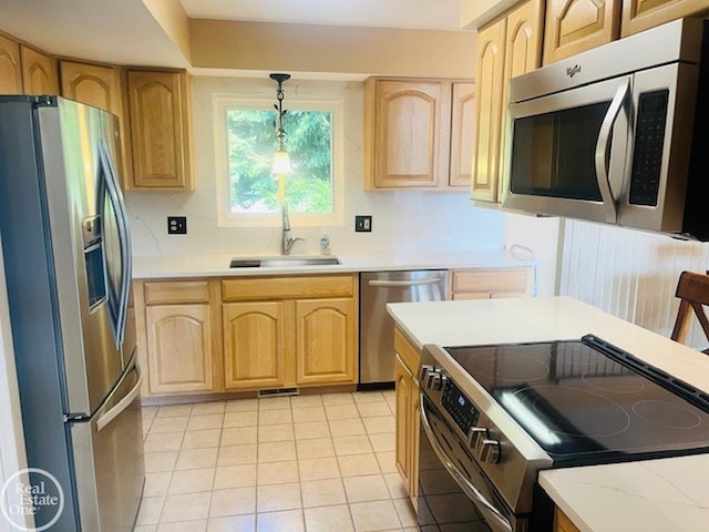 kitchen featuring a sink, decorative light fixtures, appliances with stainless steel finishes, and light brown cabinetry