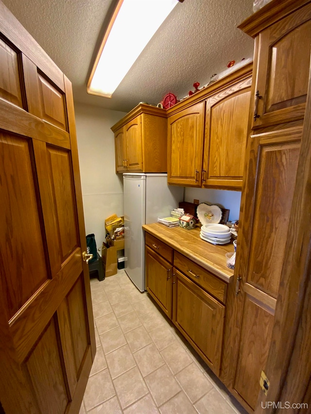 laundry area with light tile patterned flooring and a textured ceiling