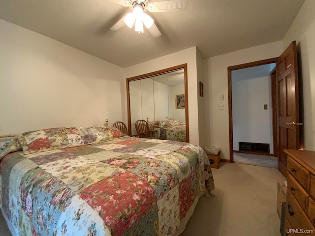 carpeted bedroom featuring ceiling fan, a closet, and a textured ceiling