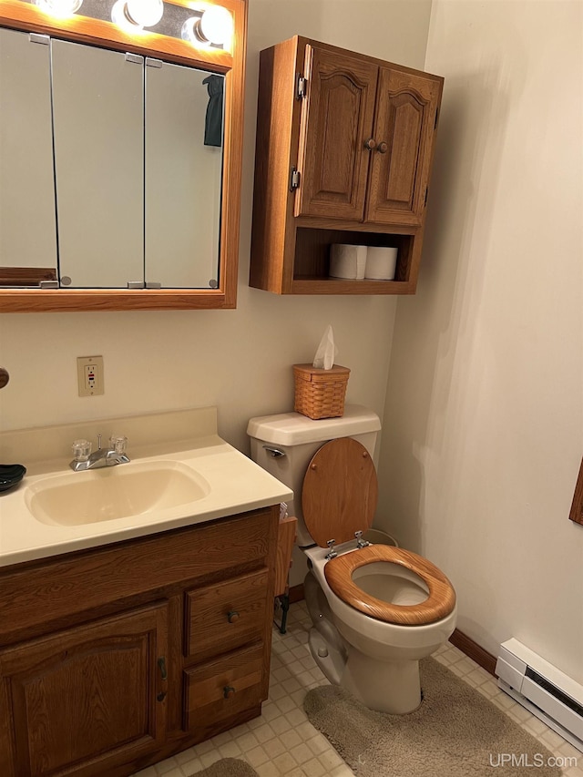 bathroom featuring baseboard heating, vanity, baseboards, tile patterned floors, and toilet