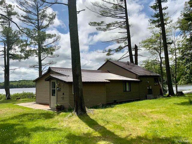 view of property exterior featuring a water view, a patio area, and a yard