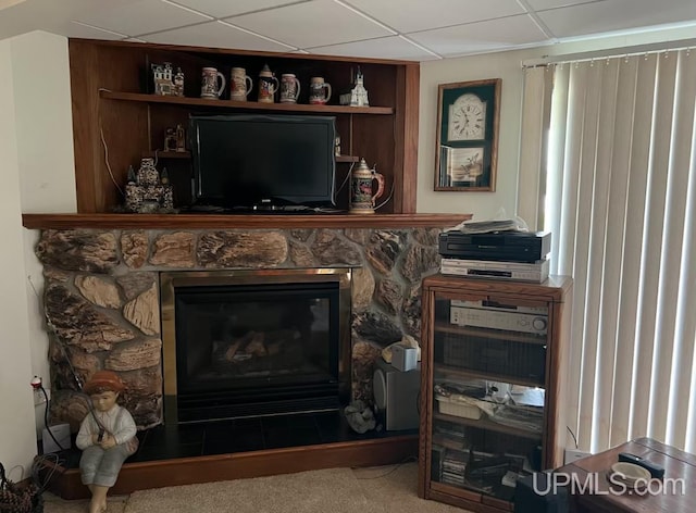 details featuring a stone fireplace, carpet flooring, and a paneled ceiling