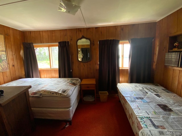 bedroom featuring wooden walls and dark colored carpet