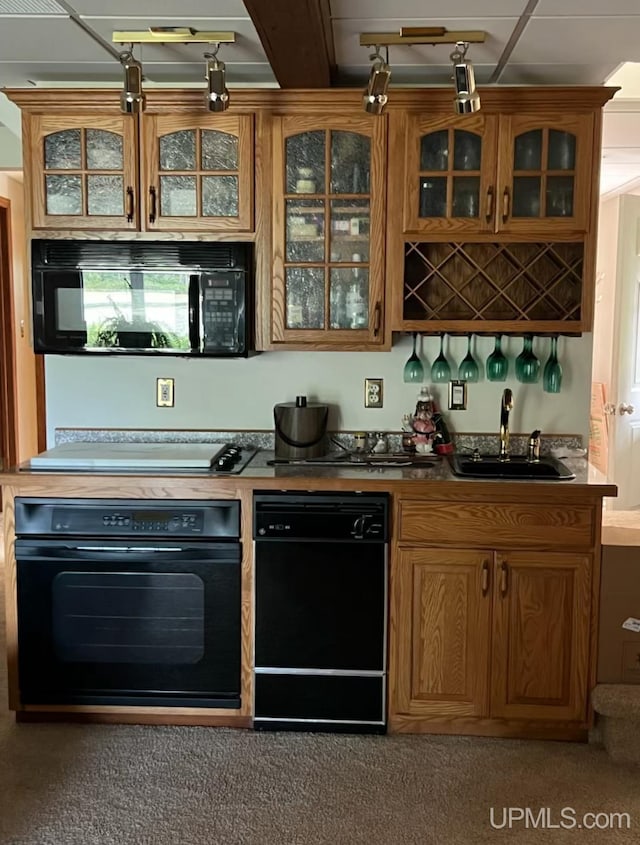 kitchen with brown cabinetry, a sink, and black appliances
