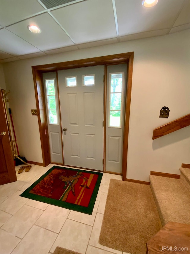 foyer entrance featuring a paneled ceiling, light tile patterned floors, and a healthy amount of sunlight