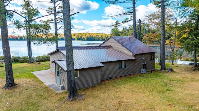 view of property exterior with a lawn, a water view, and metal roof