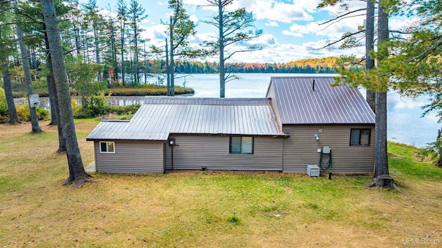rear view of property with a water view, a yard, and metal roof
