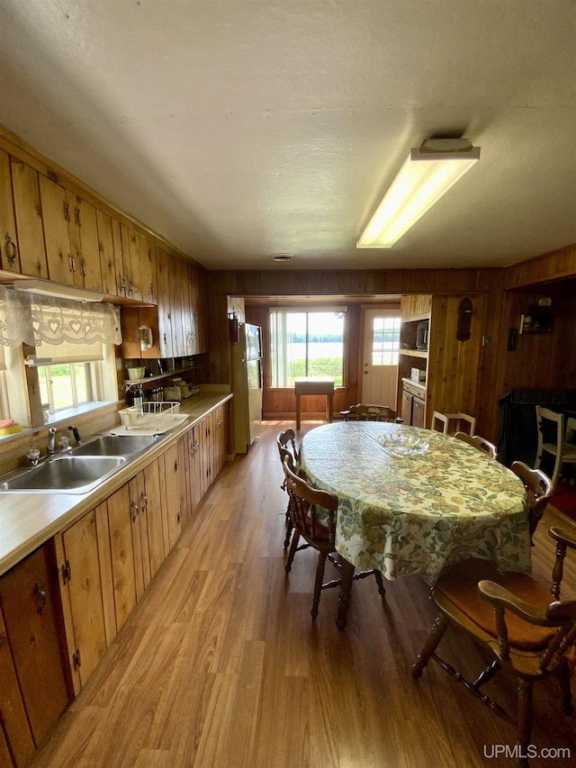 dining space with light wood-style floors, plenty of natural light, and wood walls