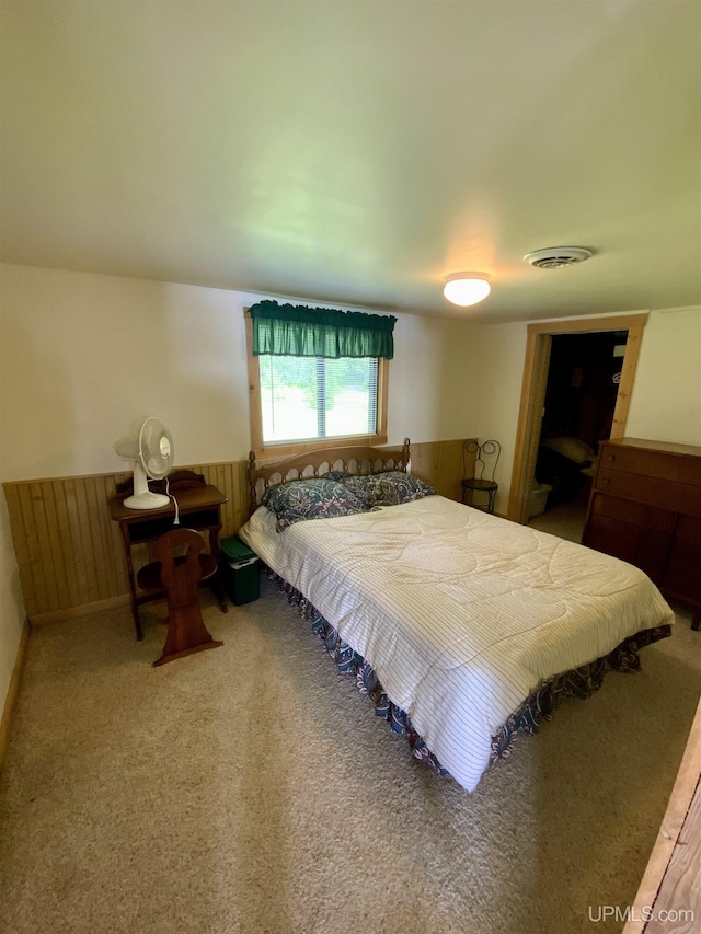 carpeted bedroom with visible vents and a wainscoted wall