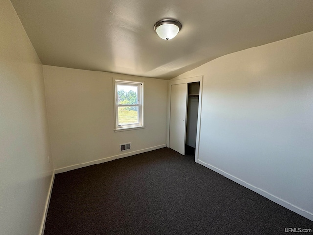 unfurnished bedroom featuring a closet, carpet, and vaulted ceiling