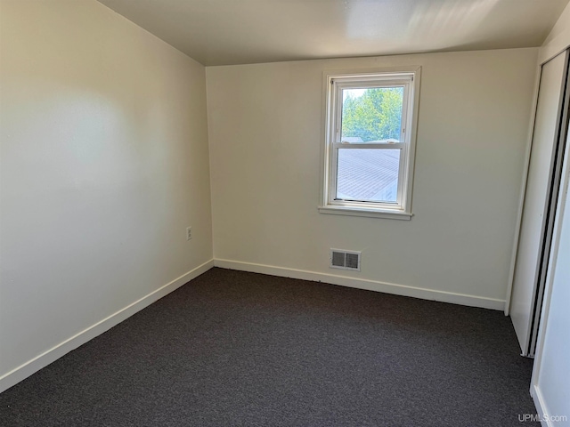 spare room featuring dark colored carpet