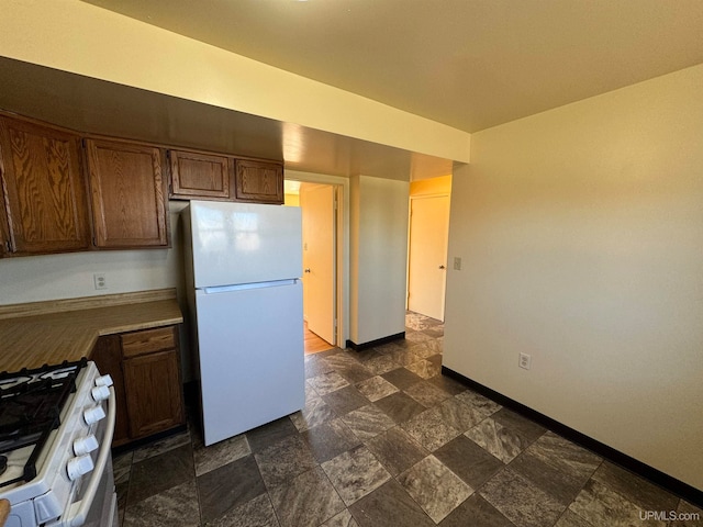 kitchen featuring dark tile patterned flooring, white refrigerator, and gas stove