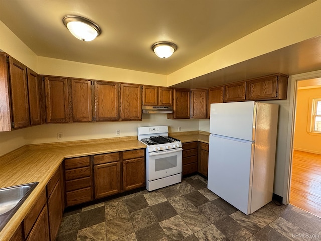 kitchen with dark wood-type flooring, white appliances, and sink