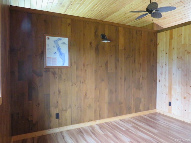 unfurnished room with ceiling fan, wood walls, wood-type flooring, and wooden ceiling