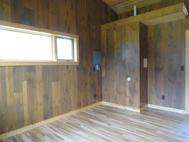 spare room featuring wood walls and light hardwood / wood-style flooring