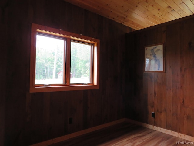 empty room with wood walls, wood ceiling, and hardwood / wood-style floors