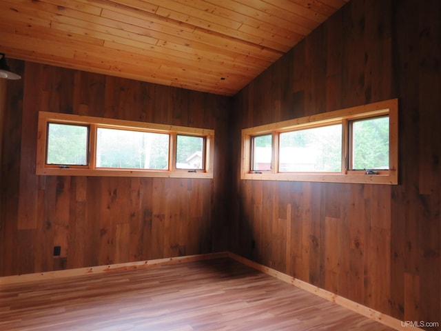 unfurnished room with wooden walls, plenty of natural light, hardwood / wood-style flooring, and wood ceiling