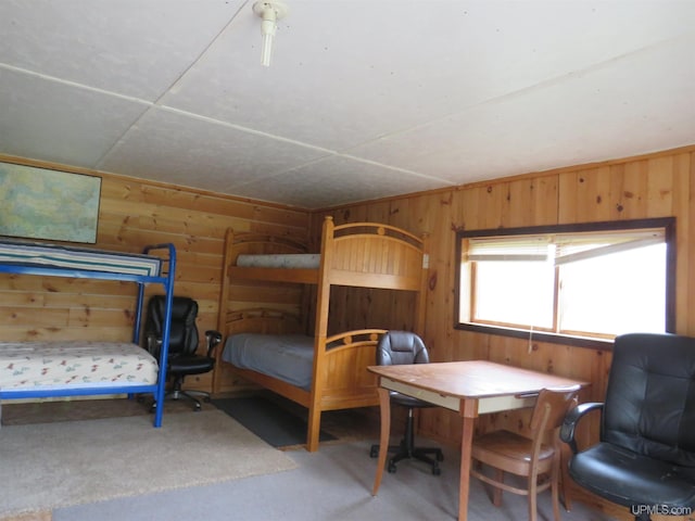 bedroom with a drop ceiling, wooden walls, and carpet floors