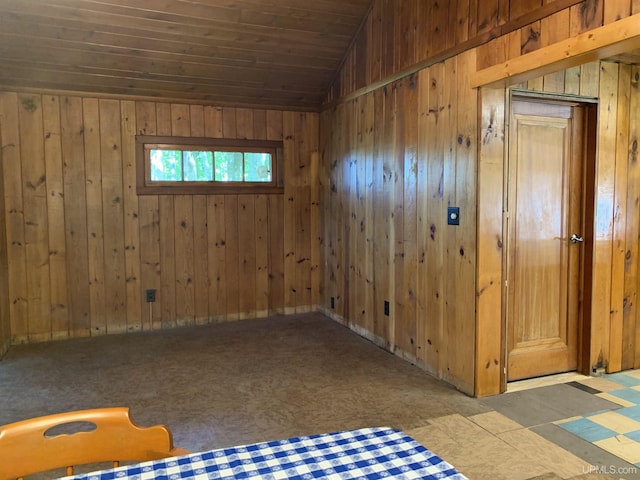 empty room featuring vaulted ceiling, wooden ceiling, and wooden walls