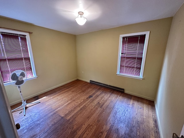 spare room with baseboard heating, baseboards, and wood finished floors