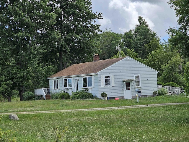 ranch-style house featuring a chimney and a front lawn