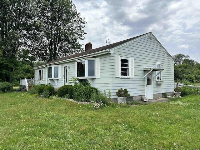 rear view of property with a chimney and a yard