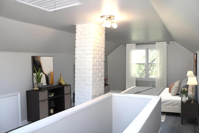 interior space featuring brick wall, ornate columns, lofted ceiling, and hardwood / wood-style floors