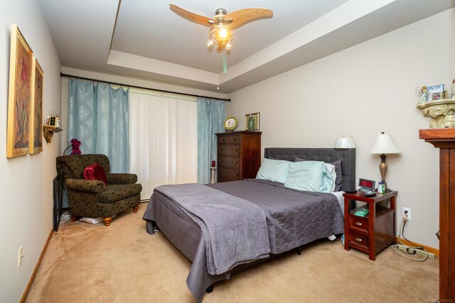 carpeted bedroom with ceiling fan and a raised ceiling