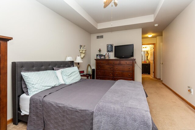 carpeted bedroom featuring ensuite bathroom, ceiling fan, and a raised ceiling