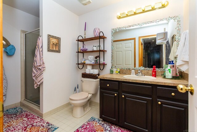 bathroom featuring tile patterned floors, vanity, a shower with door, and toilet