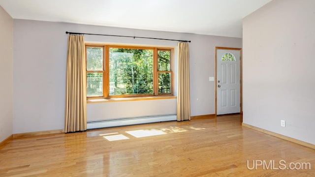 spare room with light hardwood / wood-style floors, a baseboard heating unit, and plenty of natural light